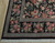 Corner detail showing layered ivory, green and burgundy guard stripes framing the black floral field