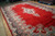 Angled view of hand-knotted wool Kerman rug showing navy border, light blue palmettes and red pile