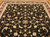Wool and silk rug photographed on hardwood floor showing black field, burgundy border, cream floral vines