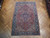 6'5" x 9'8" Persian Heriz rug laid on parquet floor showing brick red field and navy border