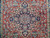 Close-up of indigo central medallion with rose rosettes and ivory outlines on brick red ground