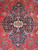 Close-up of navy medallion, ivory rosette center and multicolor floral vinework on crimson ground