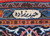 Woven signature cartouche in ivory on the blue border of this signed Persian rug