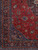 Corner detail showing navy main border, palmettes and dense floral scrollwork on red field