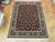 7'9" x 10' Tabriz design rug displayed on parquet showroom floor with white cotton fringe