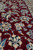 Detail of cream palmettes, blue leaves and curling vines on deep burgundy wool pile