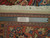 Back of the hand-knotted wool rug beside a ruler confirming fine knot count and authenticity