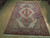 8x10 Persian Sarouk area rug angled on hardwood, showing blue pendants and paisley field detail