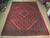 10' x 13'5" Persian Mahal rug lying flat on hardwood showroom floor, red field