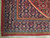 Corner close-up of navy turtle palmette border with blue guard stripes and red edge