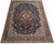 Full view of 10x13 hand-knotted wool rug showing terracotta border and dense navy floral field