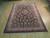 Room-size 7 x 11 Persian rug photographed lengthwise, ivory border framing dense navy floral lattice field