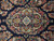 Close-up of small ivory medallion surrounded by pink, blue and olive blossoms on navy wool pile