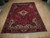 Red and ivory Heriz wool rug photographed flat on light wood floor showing corner spandrels