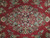 Close-up of the central floral medallion with navy, sage and ivory blossoms on red