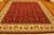Hand-knotted wool rug on hardwood floor showing deep red field and cream border with paisley motifs