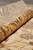Rolled edge revealing dense silky wool pile and the gold border drawing in close detail
