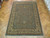 8'10" x 12'1" hand-knotted wool rug laid across herringbone parquet floor in showroom