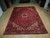 9x13 red Heriz rug shown lengthwise on hardwood with ivory spandrels and dark border