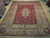 9'7" x 13' Persian Kerman rug laid flat on showroom hardwood, deep red floral field