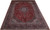 Angled floor view of a 10 x 14 Kashan rug showing red field and navy floral border