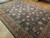 Angled view of 10x14 traditional wool rug showing black ground, olive guard borders and ivory palmettes