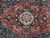 Close up of charcoal and ivory medallion surrounded by hand knotted floral sprays on red field