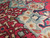 Close-up of hand-knotted wool pile with celadon blue palmettes, ivory blossoms and crimson medallion detail