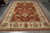 Hand-knotted Indian Agra rug in rust and ivory displayed on grey showroom floor, full view