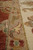 Border detail where the rust field meets camel guard stripe and ivory main border