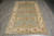 Indian Oushak rug in 6 by 9 size laid flat on gray plank floor, overhead view