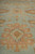 Low angle macro of hand-knotted wool pile with salmon and gold medallion on pale blue ground