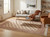 Living room styled with cream Bokhara wool rug under wood coffee table and linen sofa