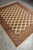 Hand-knotted Pakistani Bokhara rug photographed lengthwise showing brown guard borders and stepped diamond medallions