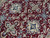 Close-up of ivory and blue lobed rosettes, flowering vines and silk highlights on burgundy pile