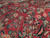 Detail of the soft red field showing hand-knotted floral sprays in salmon, teal and ivory wool