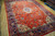 Angled daylight view showing the coral red field, navy main border and ivory corner spandrels