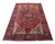 Angled floor view of red Heriz area rug showing ivory corner spandrels and navy border
