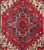 Close-up of the stepped geometric medallion in navy, ivory and rust on red wool pile