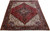 Angled floor view of a red and ivory hand-knotted Heriz wool rug in 9x12 size