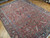 Angled floor view of hand-knotted wool Persian rug with palmettes, blue rosettes and soft rose tones