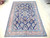 7' x 10'4" semi antique Sarouk rug displayed on pale wood floor showing full navy field