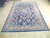 Rose and sky blue borders frame the dark blue field of this hand-knotted floral rug
