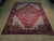 8' x 11' Persian Heriz rug photographed at an angle, full length red field and layered borders