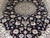 Close-up of ivory and blue medallion surrounded by delicate black field floral vines in wool and silk