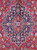 Close-up of navy lobed medallion with red cusped core, palmettes and ivory outlined scrolling vines