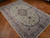 6'4" x 9'8" light green Nain rug angled on parquet, showing scrolling vine field and borders