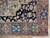 Corner detail showing navy spandrel, salmon rose border rosettes and hand-knotted wool selvedge