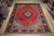9'8" x 12'3" Persian Sarouk rug laid on warehouse wood floor beside rolled Persian rugs