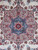 Close-up of rose and blue 8 point medallion with red star center on ivory wool
